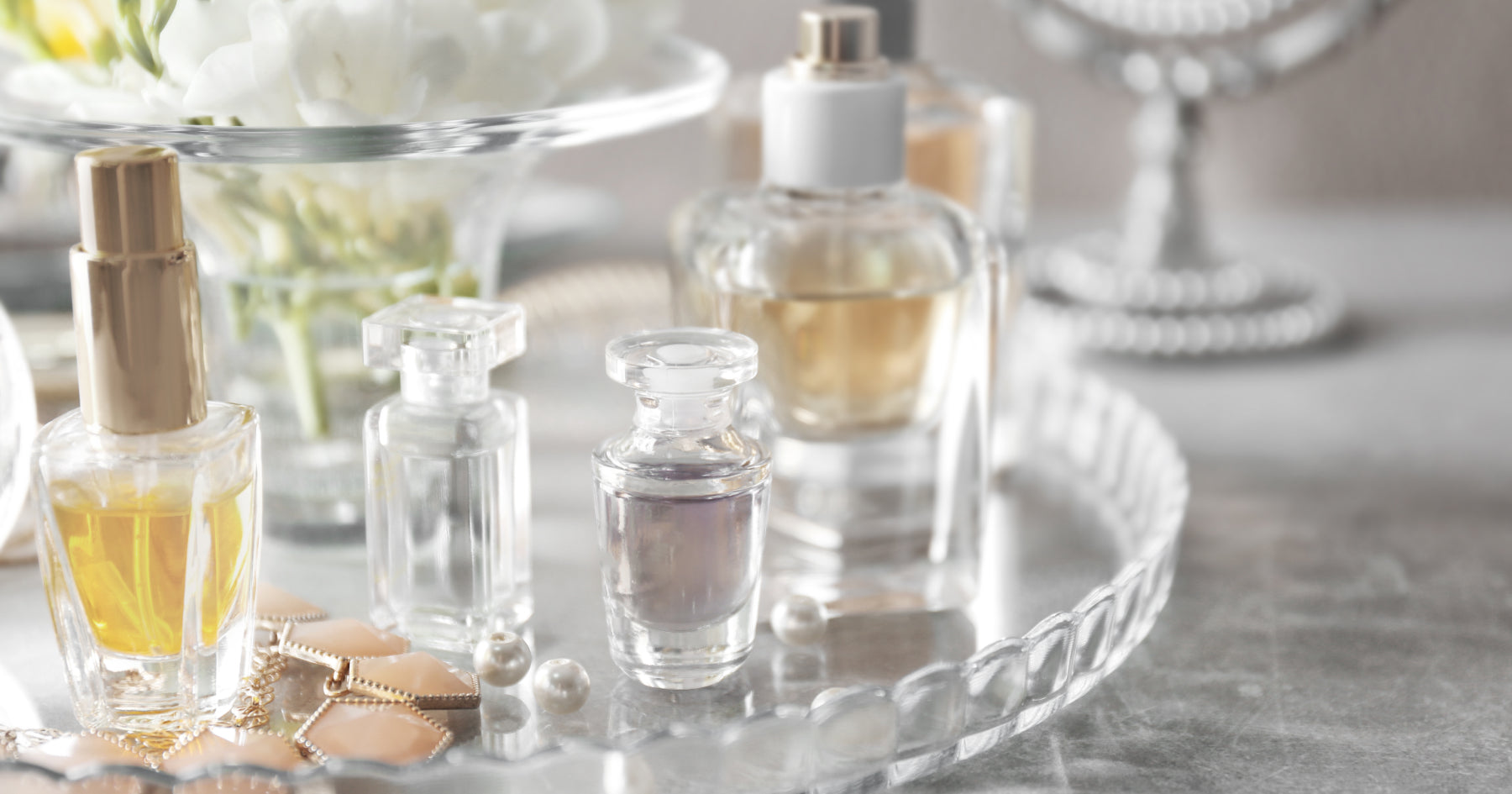 透明のトレーに香水とアクセサリーが並んでいる