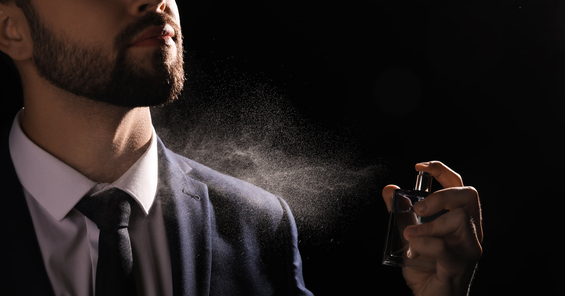 首元に香水を振っているスーツの男性